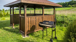 Wooden summer house with grill in the backyard