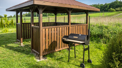 Wooden summer house with grill in the backyard